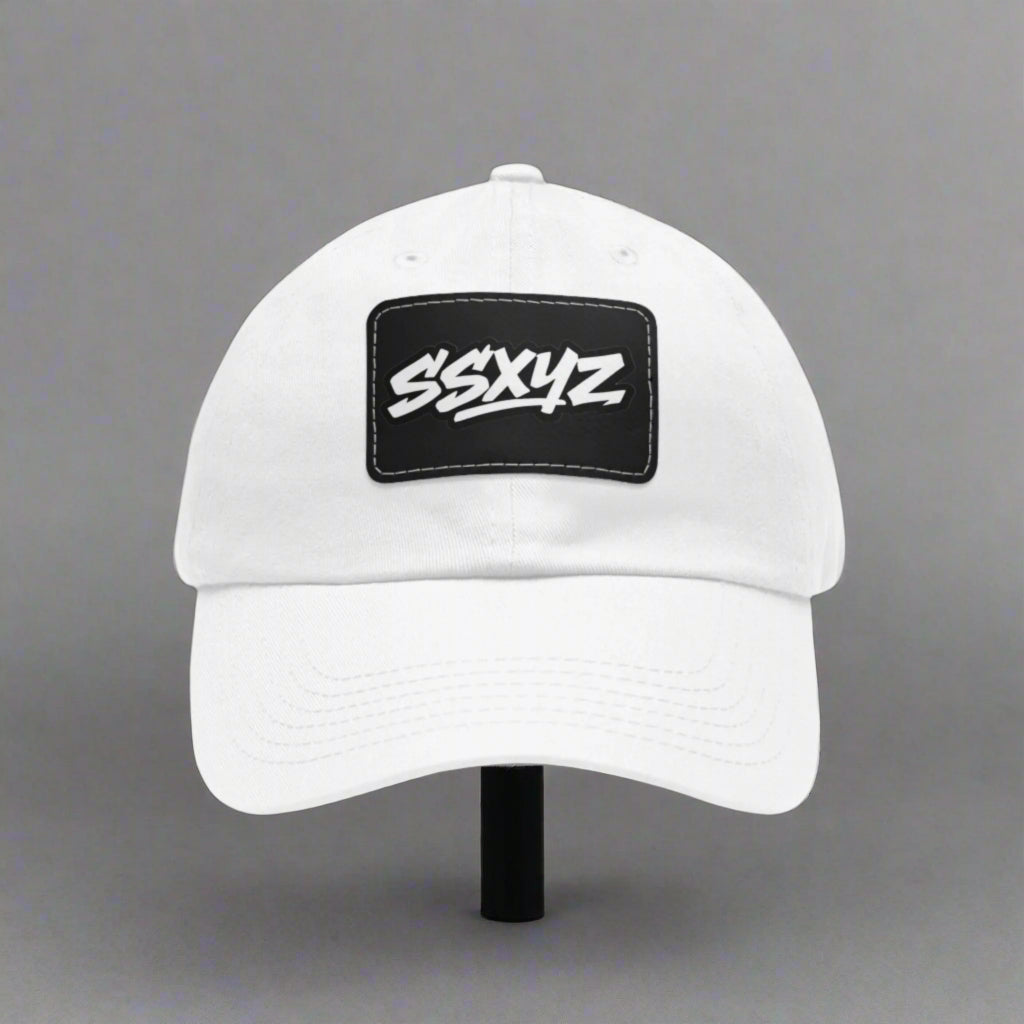 White dad hat with a black rectangular patch on the front displaying the white text "SSXYZ", the shorthand logo for Stylesavvy.xyz. The hat has a curved brim and an adjustable back strap.